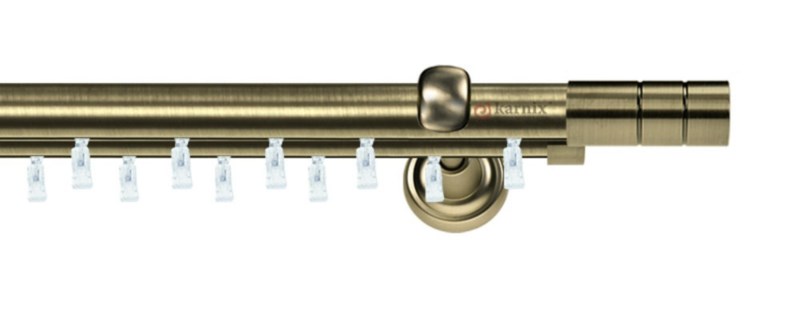 Kovová dvouřadá garnýž Aspen Cylinder v mosazné barvě. Tyče o průměru 25 a 19 mm umožňují plynulý pohyb závěsů po celé délce.